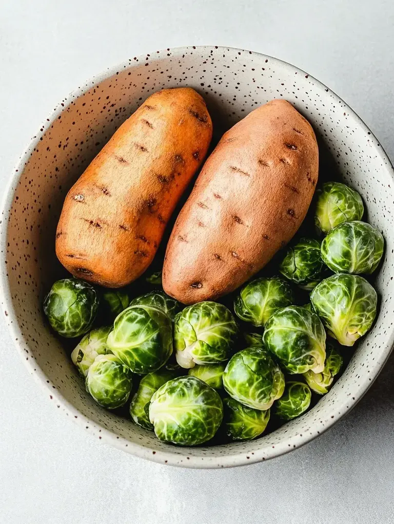 Eine Schüssel mit zwei Süßkartoffeln und mehreren grünen Rosenkohl-Röschen.
