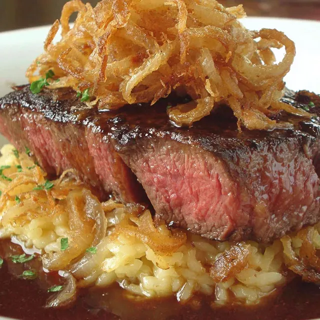 A plate of meat with onions on top.