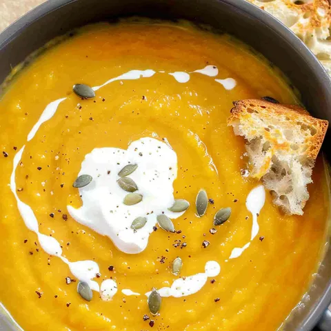 A bowl of soup with a piece of bread on top.