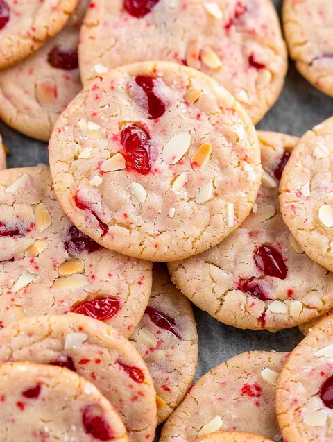 A pile of cookies with cherries on top.