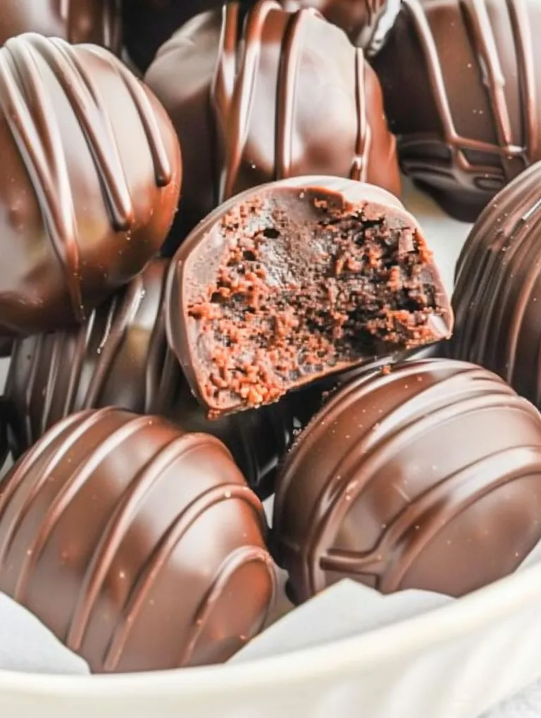 A close up of a chocolate truffle with a bite taken out of it.