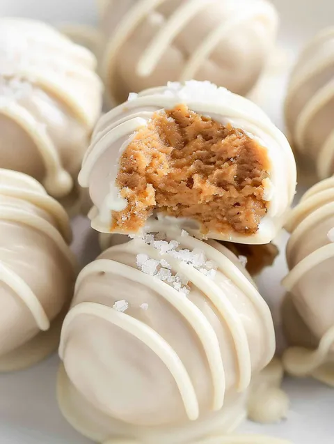 A white chocolate peanut butter ball with a bite taken out of it.