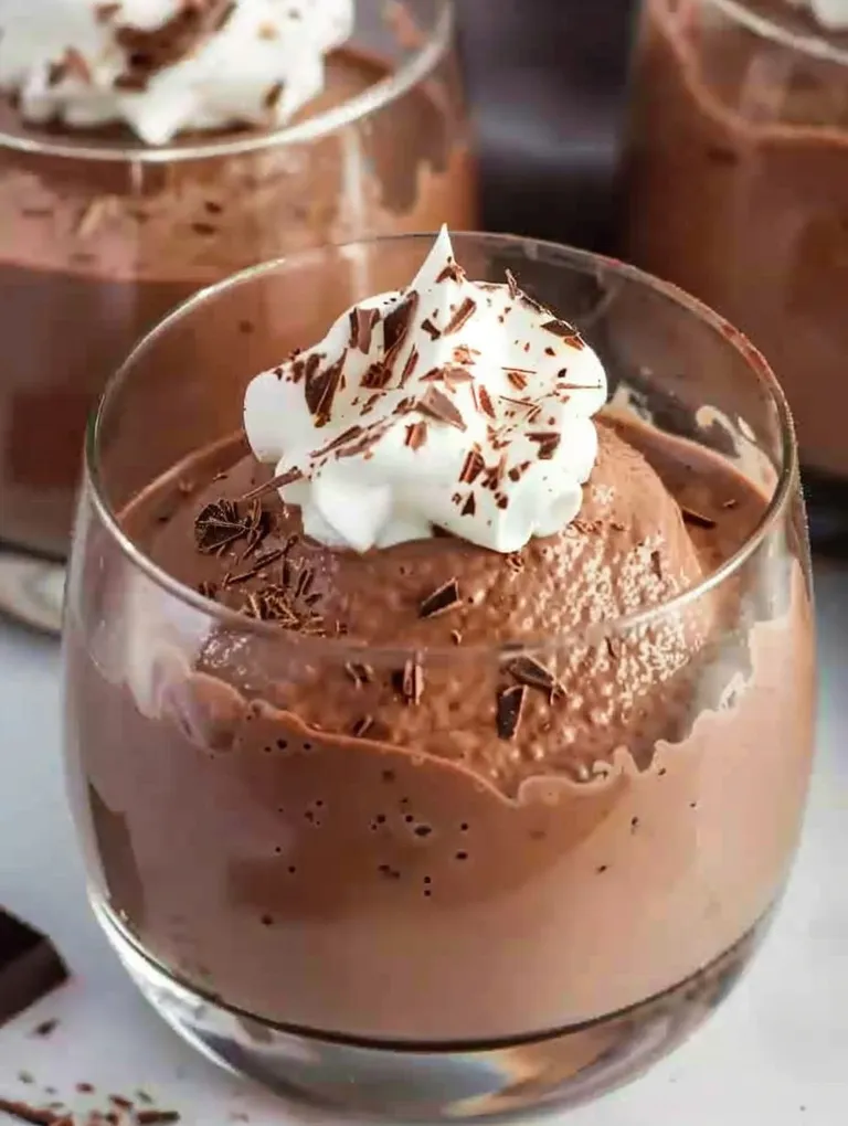 A glass of mousse au chocolat with whipped cream on top.