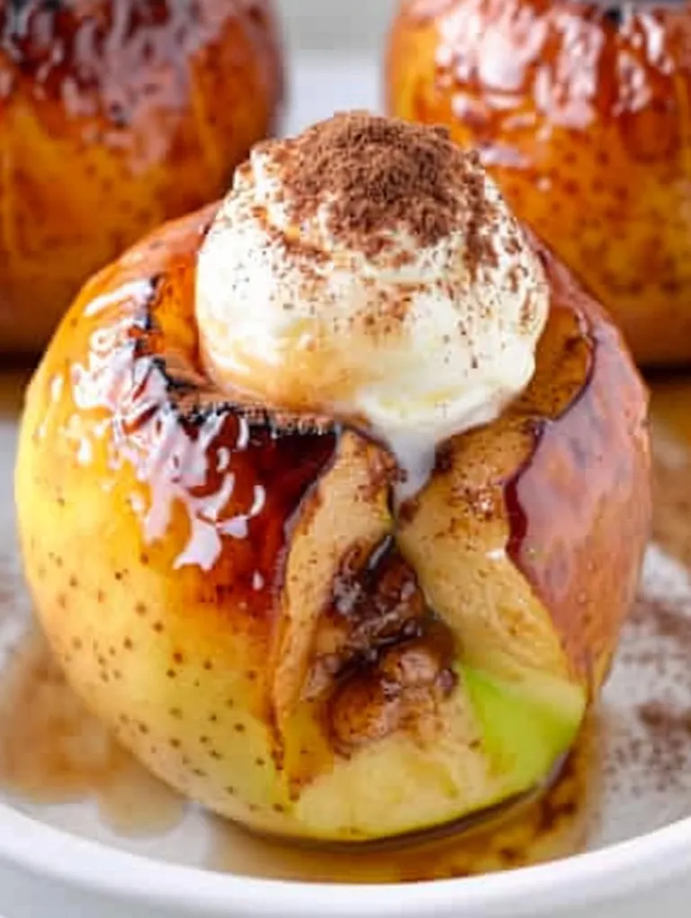 A baked apple with a dollop of whipped cream on top.