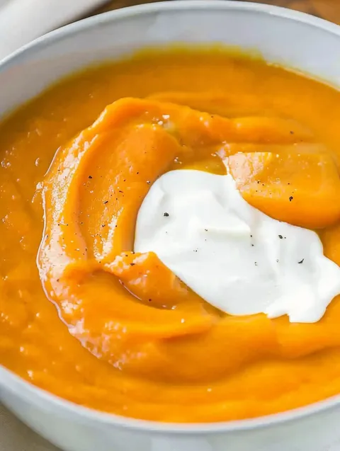 A bowl of creamy potato carrot soup.