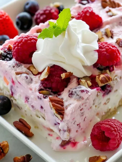 A slice of frozen berry fruit salad with whipped cream on top.