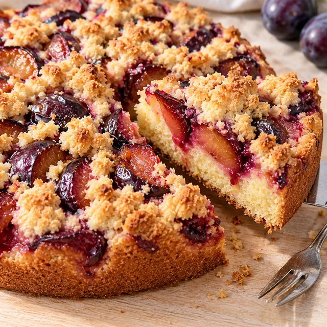 Pflaumenkuchen mit Streuseln und saftigen Zwetschgen auf einer Holzplatte